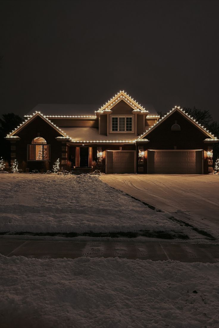 Two-story home outlined in warm white C9 Christmas lights on a snowy night