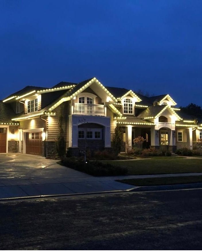 Large craftsman home outlined in warm white Christmas roofline lights